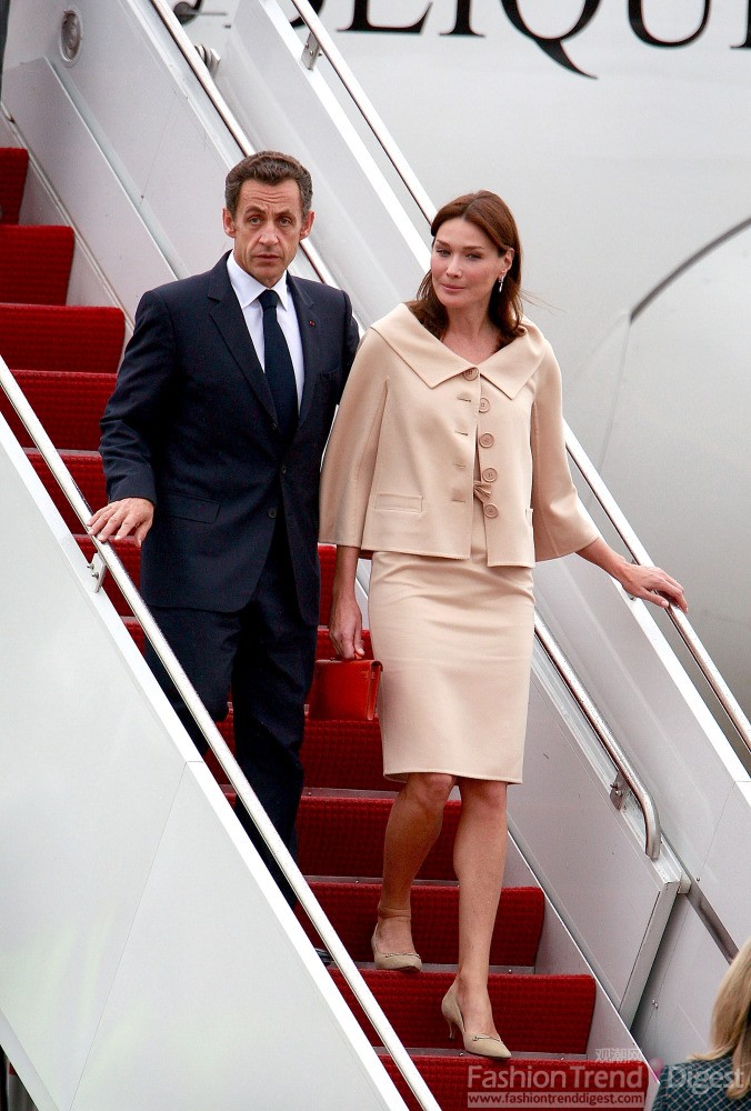 8. 卡拉•布吕尼（Carla Bruni-Sarkozy）与丈夫参加政治活动，身着的是一套粉色套裙，手提红色手提包。