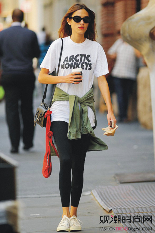 英伦It Girl艾里珊·钟(Alexa Chung)白色简洁的字母T，搭配黑色紧身裤，军绿色衬衫的绑系，点亮整套搭配。黑色墨镜和红唇，彰显出钟小姐的非凡魅力气质。